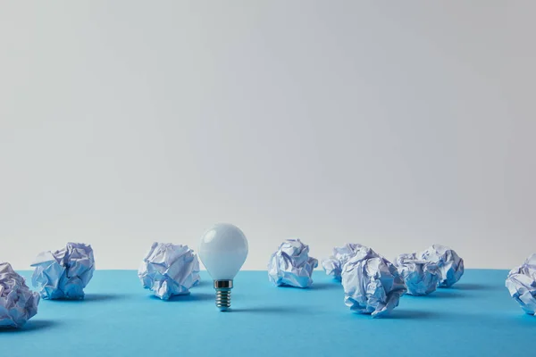 Close Shot Power Saving Light Bulb Crumpled Papers Blue Surface — стоковое фото